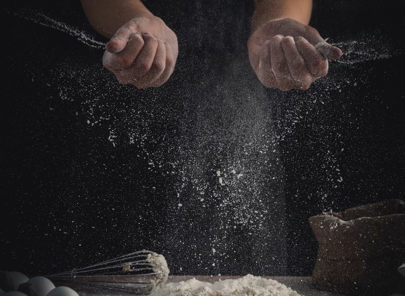 Flour being worked by hand above a preparation surface