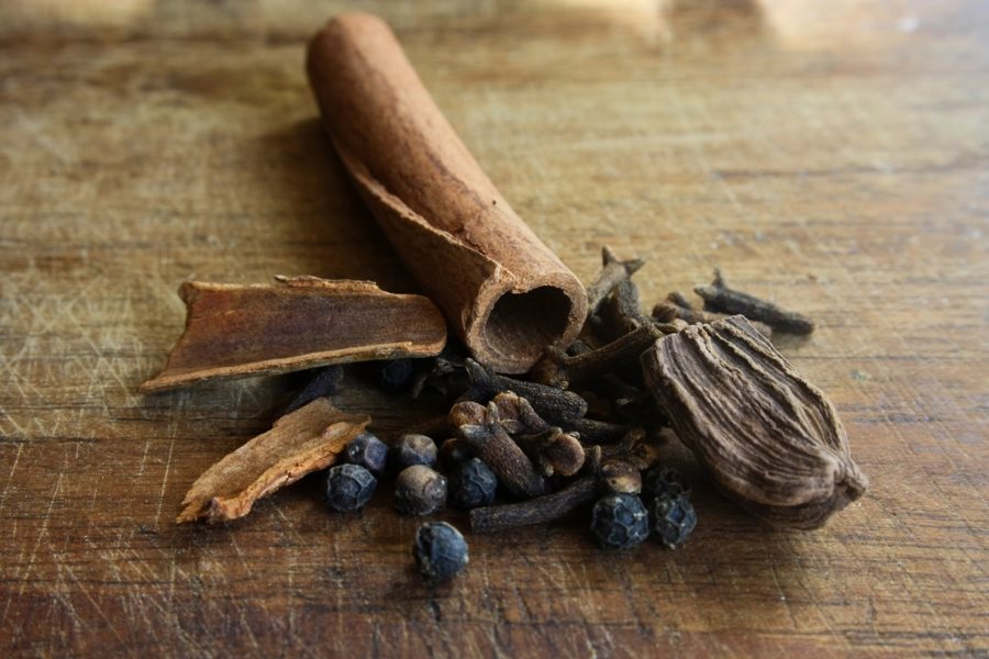 Whole Indian spices including cinnamon, cardamom and cloves on wood